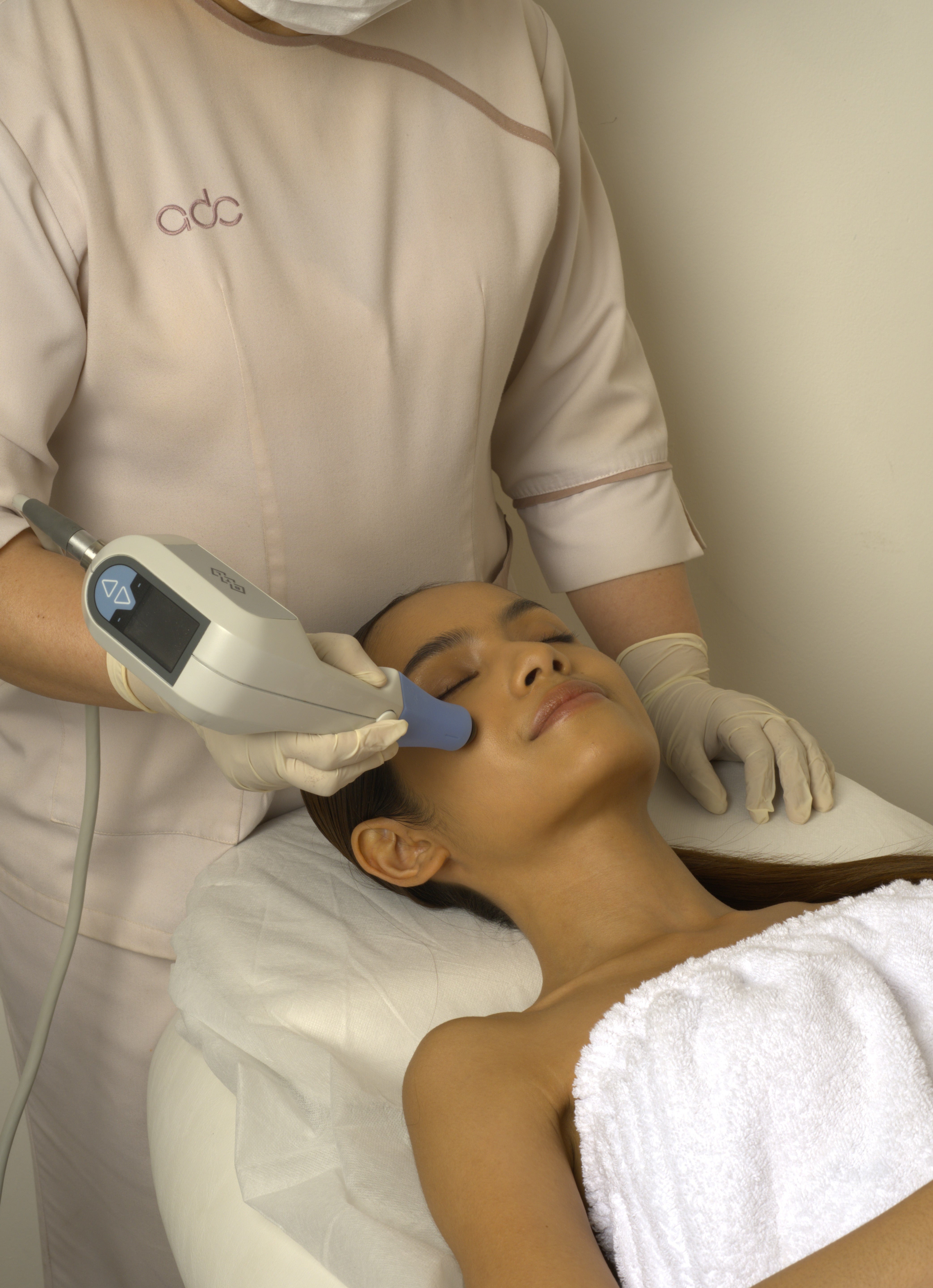 Person receiving an Exilis Ultra 360 facial treatment with a device in a clinic setting