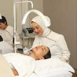 A woman receiving an Exion facial treatment in a clinical setting with another person assisting.