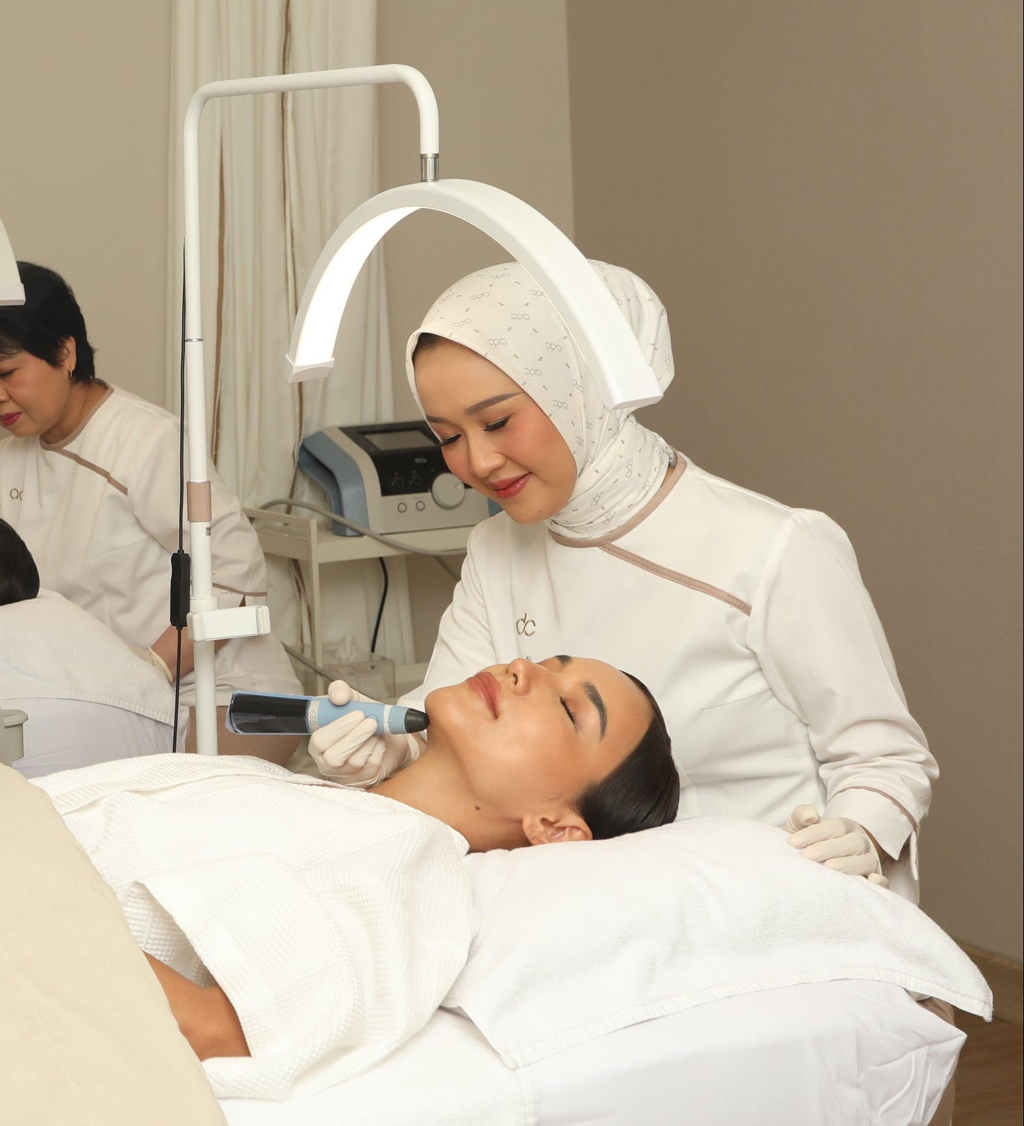 A woman receiving an Exion facial treatment in a clinical setting with another person assisting.