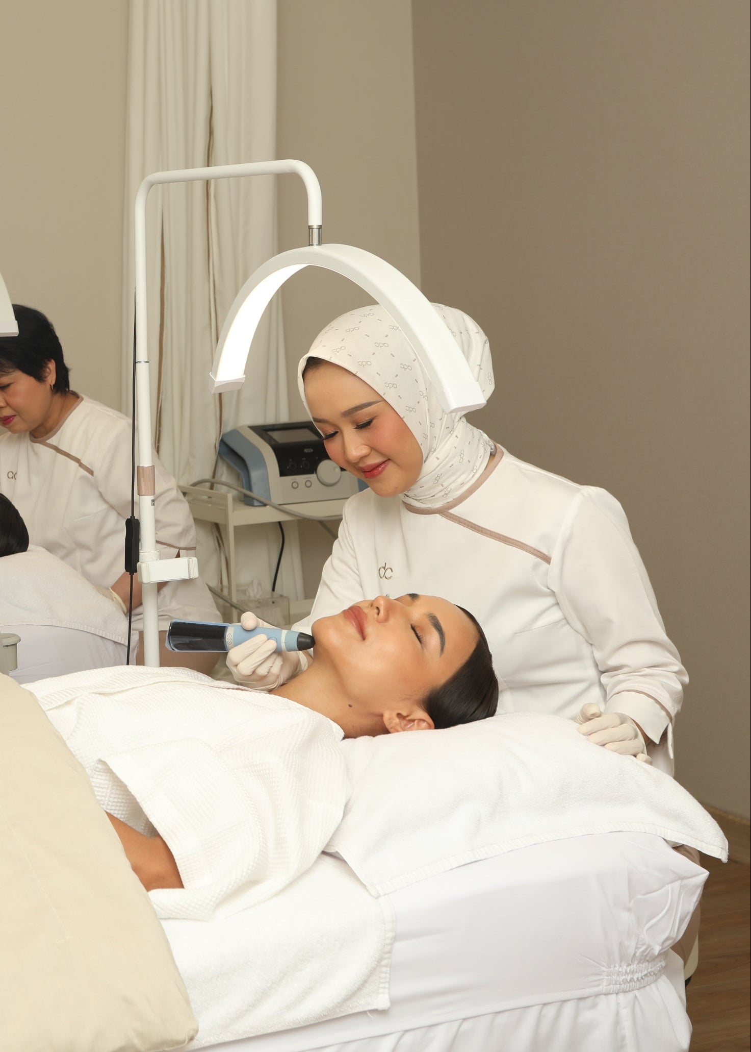 A woman receiving an Exion facial treatment in a clinical setting with another person assisting.