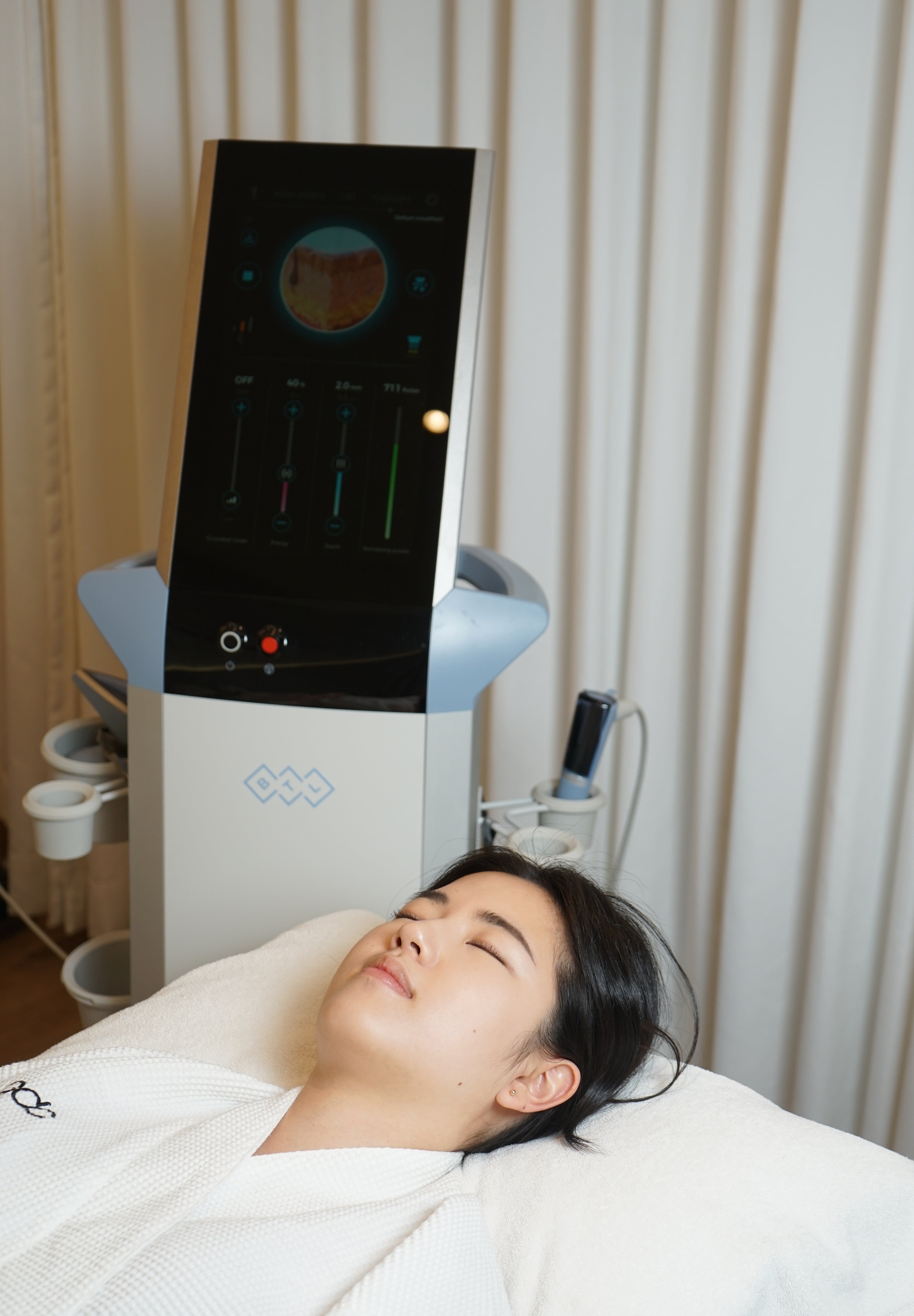 Person lying on a white mat with a Microneedling RF device displaying a graph.
