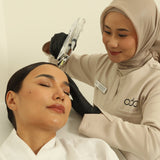 A woman receiving a Premium Hair Growth treatment from another woman in a beige hijab against a plain background